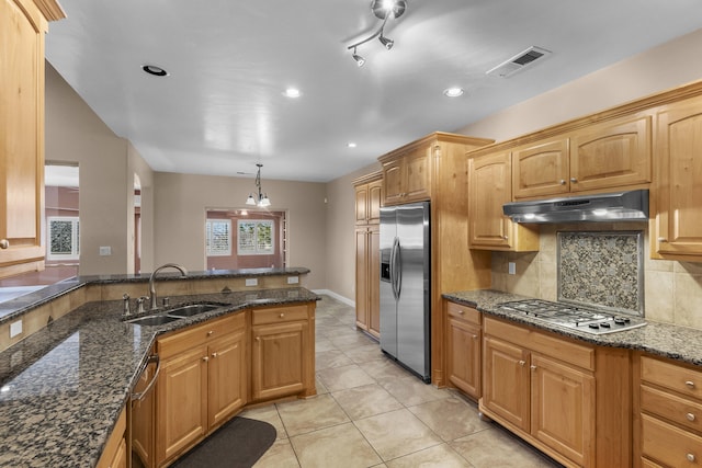 kitchen with pendant lighting, sink, appliances with stainless steel finishes, decorative backsplash, and dark stone counters