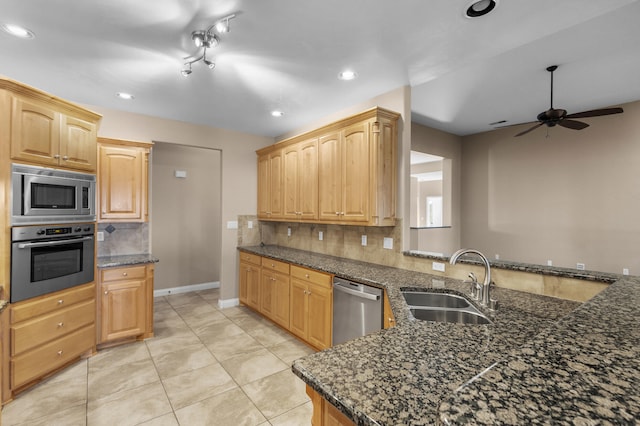 kitchen featuring sink, dark stone countertops, appliances with stainless steel finishes, kitchen peninsula, and decorative backsplash