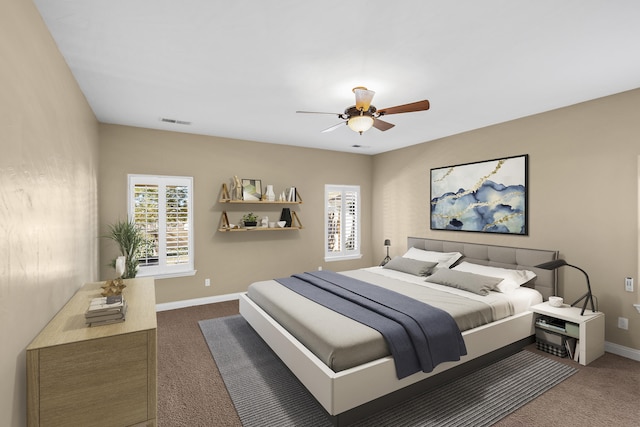 bedroom with multiple windows, dark carpet, and ceiling fan