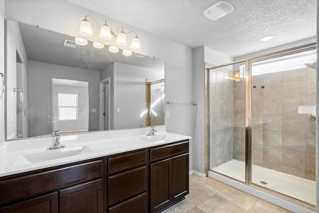 bathroom featuring a shower with door, vanity, tile patterned flooring, and a textured ceiling