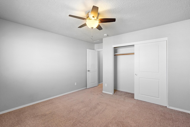 unfurnished bedroom featuring a textured ceiling, light colored carpet, a closet, and ceiling fan