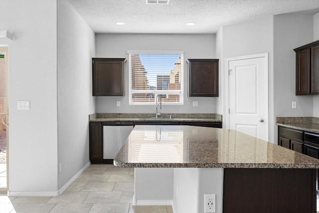 kitchen with sink, a center island, stainless steel dishwasher, dark brown cabinets, and a textured ceiling