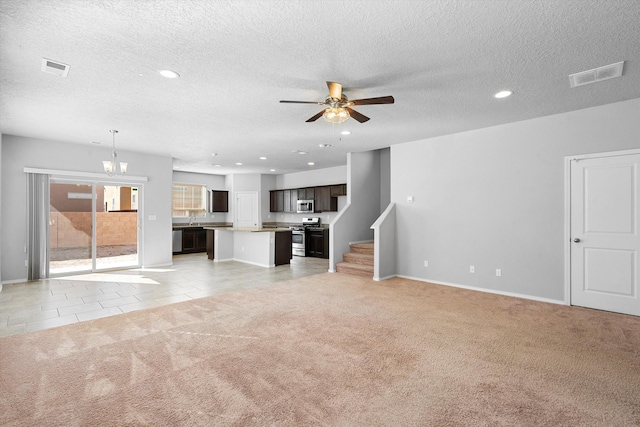 unfurnished living room with sink, ceiling fan with notable chandelier, light colored carpet, and a textured ceiling