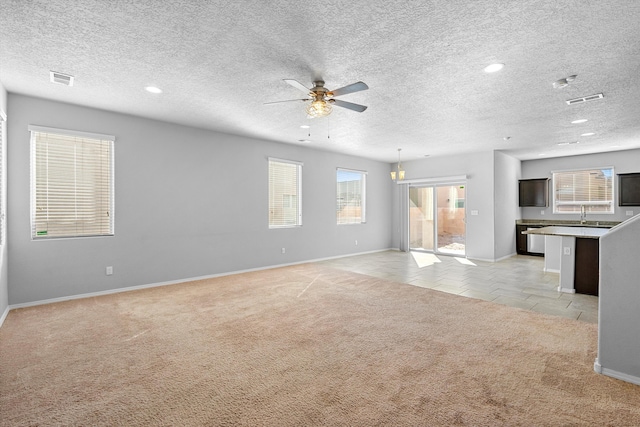 unfurnished living room with sink, light carpet, a textured ceiling, and ceiling fan