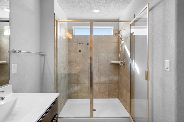 bathroom featuring vanity, an enclosed shower, and a textured ceiling