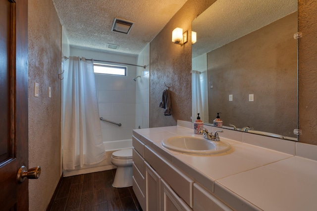 full bathroom featuring vanity, a textured ceiling, shower / bath combination with curtain, and toilet