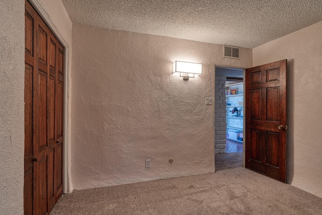 empty room with a textured ceiling and carpet