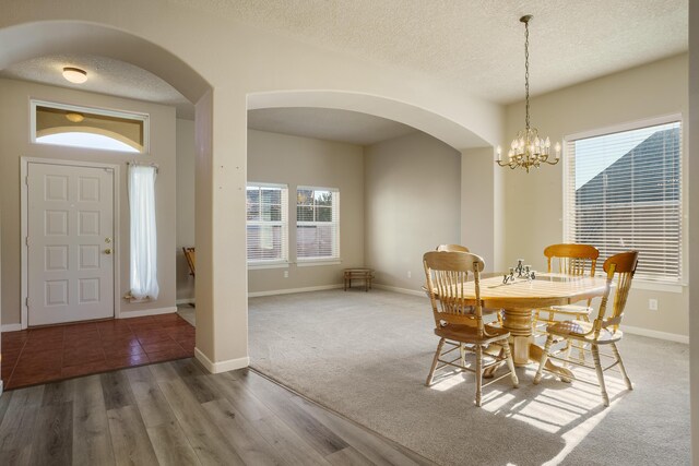 dining room featuring a notable chandelier, baseboards, a textured ceiling, and wood finished floors