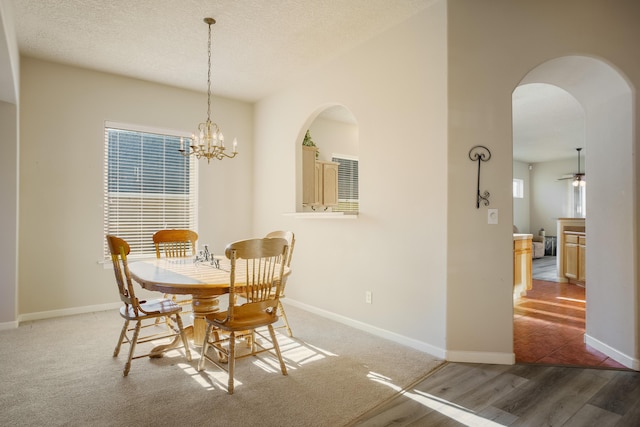 dining area featuring baseboards, a textured ceiling, arched walkways, and an inviting chandelier