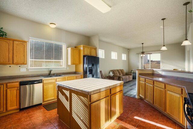 kitchen featuring a sink, black fridge with ice dispenser, stainless steel dishwasher, a center island, and decorative light fixtures