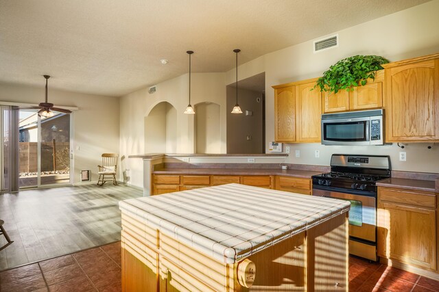 kitchen featuring a textured ceiling, stainless steel appliances, light brown cabinets, and visible vents