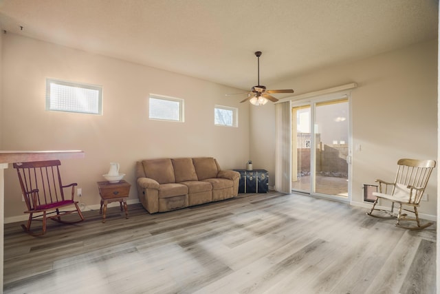 living area featuring a ceiling fan, baseboards, and wood finished floors