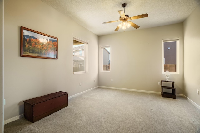 unfurnished bedroom with light carpet, a textured ceiling, a ceiling fan, and baseboards