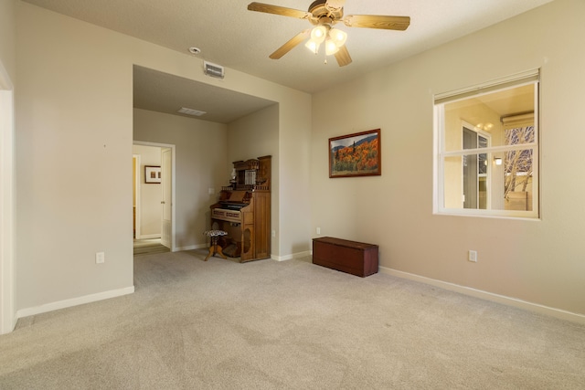 carpeted spare room with baseboards, visible vents, and a ceiling fan