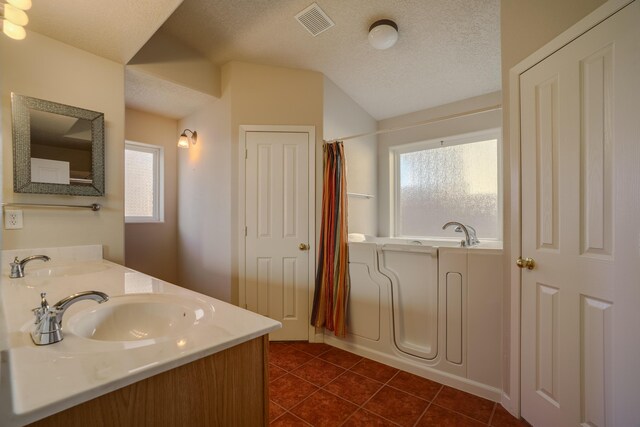 bathroom featuring a textured ceiling, a sink, a bathtub, and tile patterned floors