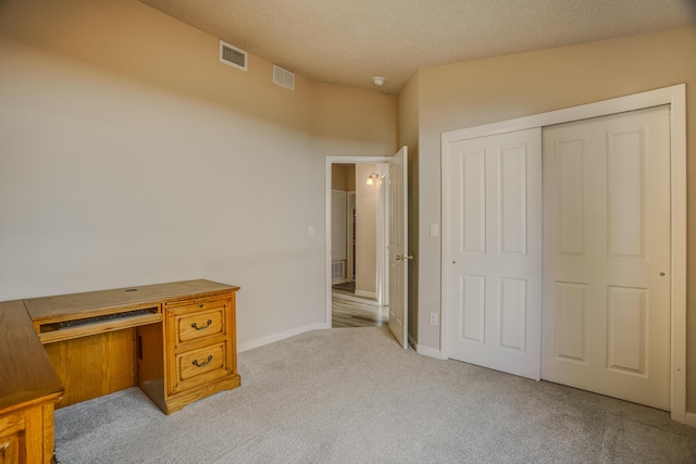 carpeted home office featuring visible vents, a textured ceiling, and baseboards