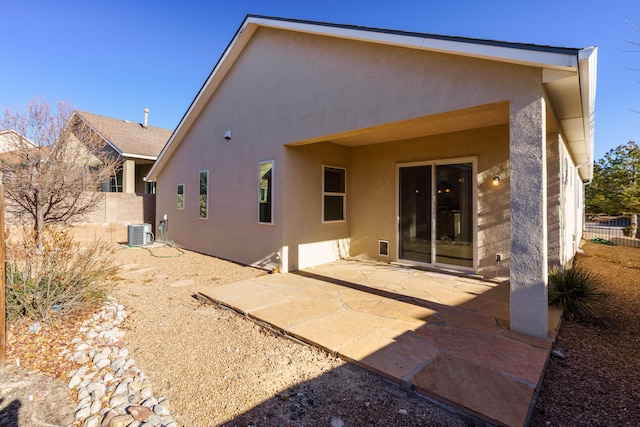 rear view of house featuring a patio area, central AC, fence, and stucco siding