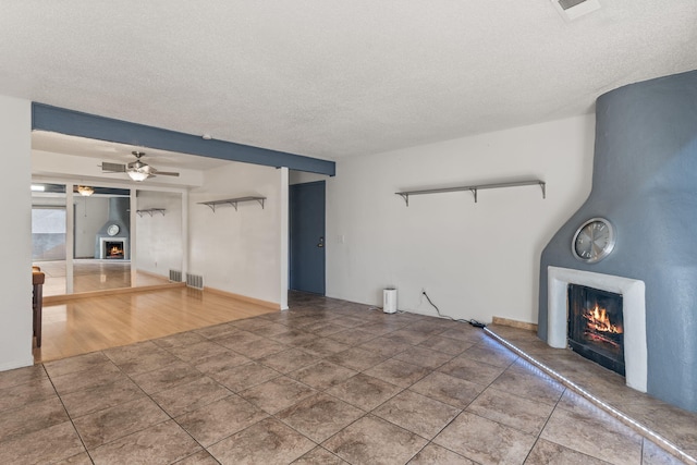 unfurnished living room with tile patterned flooring, ceiling fan, and a textured ceiling