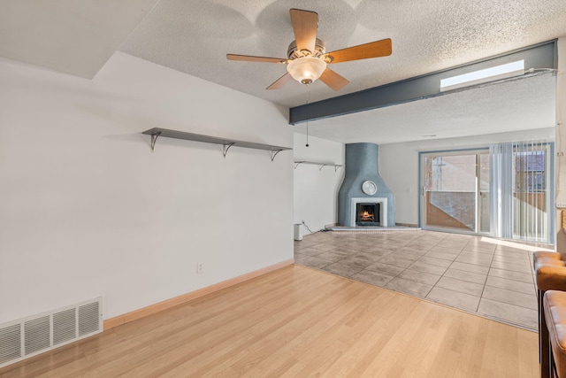 unfurnished living room featuring a textured ceiling, light hardwood / wood-style flooring, and ceiling fan