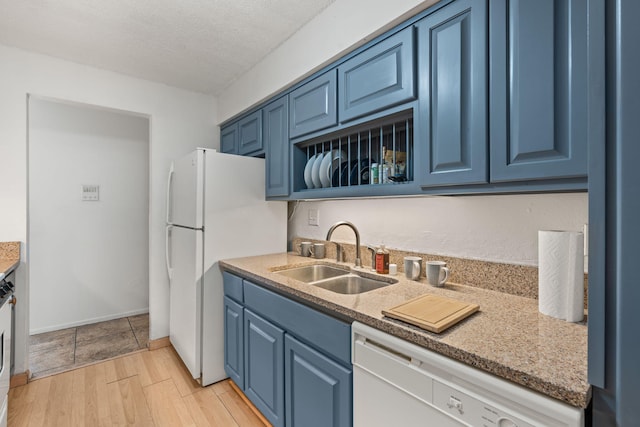 kitchen featuring sink, white appliances, light hardwood / wood-style flooring, a textured ceiling, and blue cabinets