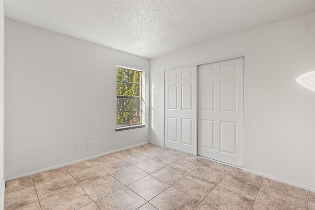 unfurnished bedroom with light tile patterned floors, a closet, and a textured ceiling