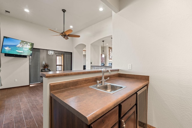 kitchen featuring lofted ceiling, sink, dark hardwood / wood-style flooring, ceiling fan, and dark brown cabinets