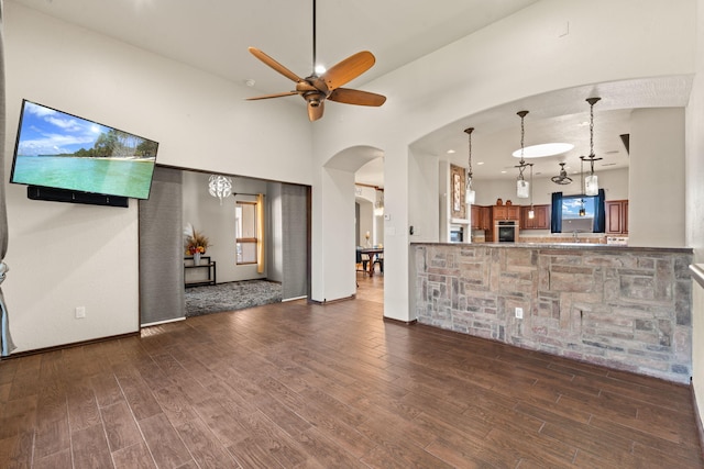 unfurnished living room with dark wood-type flooring, ceiling fan, and high vaulted ceiling