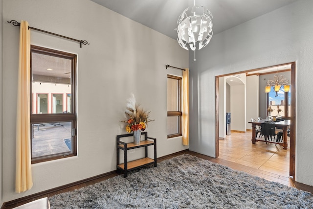 hallway with tile patterned flooring, plenty of natural light, and a chandelier