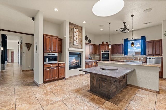 kitchen featuring a kitchen island, a fireplace, backsplash, hanging light fixtures, and stainless steel double oven