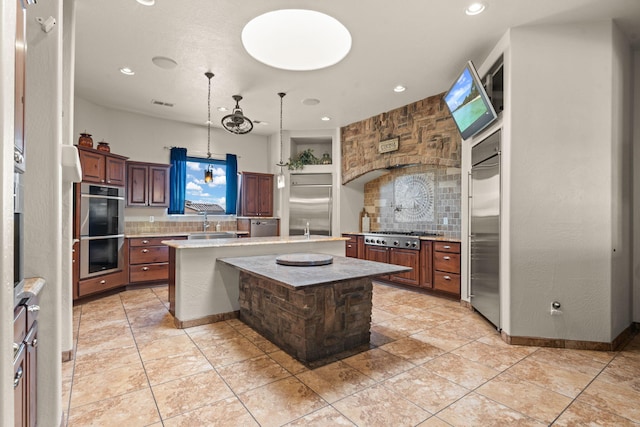 kitchen featuring pendant lighting, built in features, stainless steel appliances, a center island, and tasteful backsplash