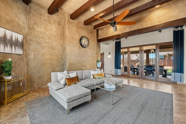 tiled living room featuring ceiling fan, a towering ceiling, beam ceiling, and french doors