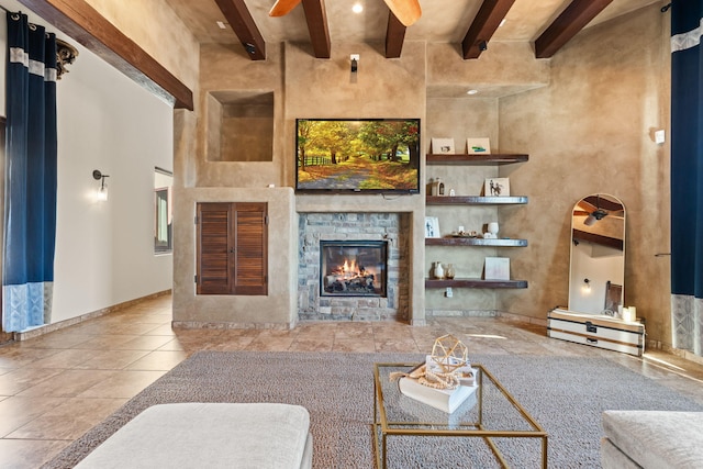 living room with ceiling fan, a towering ceiling, a fireplace, and beam ceiling