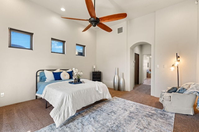 carpeted bedroom with multiple windows, a towering ceiling, and ceiling fan