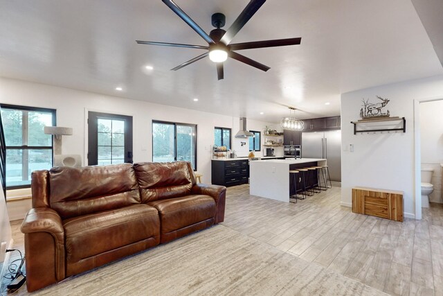 living area with recessed lighting, baseboards, light wood-type flooring, and a ceiling fan