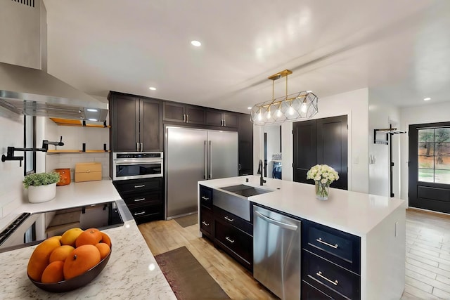 450 Juan Tomas Rd, Tijeras, NM 87059 - kitchen featuring stainless steel appliances, range hood, light countertops, light wood-style floors, and decorative backsplash
