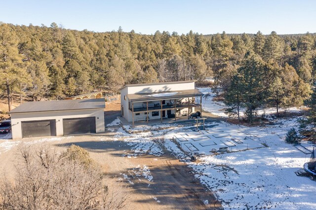 view of front facade with an outbuilding, stucco siding, a view of trees, and a garage