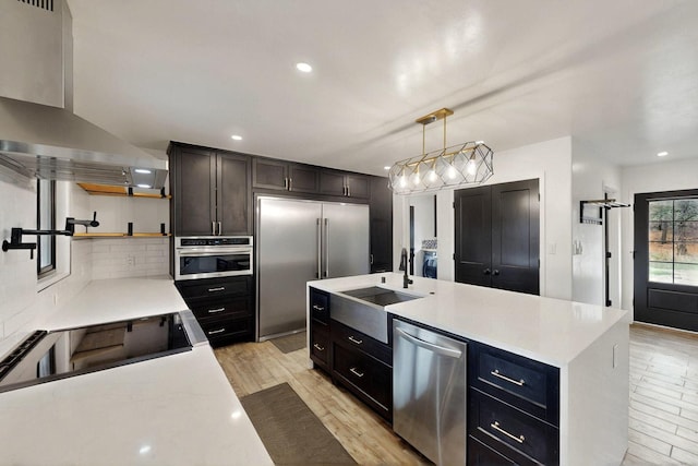 450 Juan Tomas Rd, Tijeras, NM 87059 - kitchen featuring stainless steel appliances, wall chimney range hood, open shelves, backsplash, and light wood finished floors