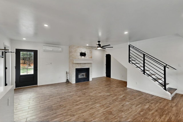 450 Juan Tomas Rd, Tijeras, NM 87059 - unfurnished living room with an AC wall unit, a ceiling fan, wood finished floors, stairway, and a large fireplace