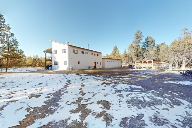 snow covered back of property featuring a garage