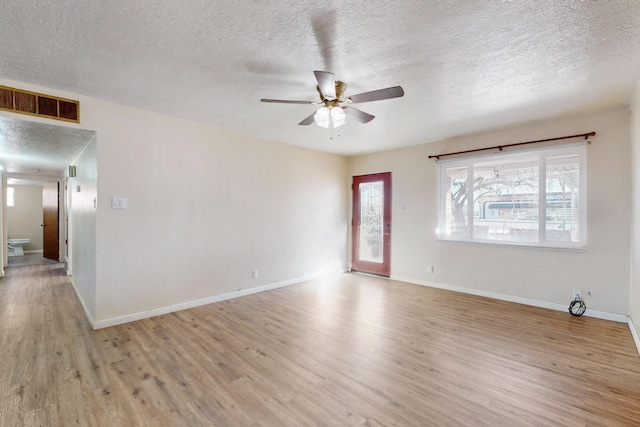 empty room with ceiling fan, light hardwood / wood-style floors, and a textured ceiling