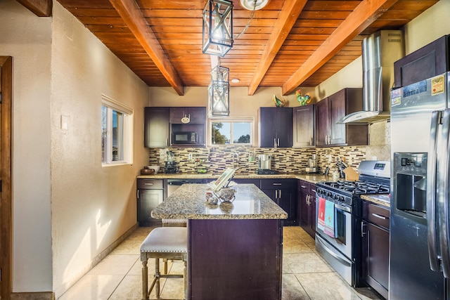 kitchen with wall chimney range hood, hanging light fixtures, stainless steel appliances, a center island, and dark brown cabinetry