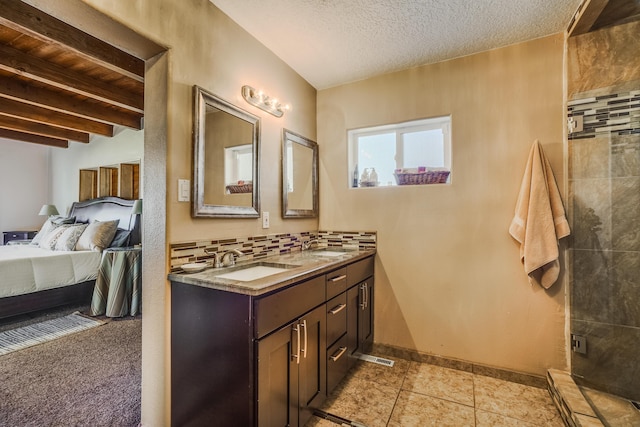 bathroom with vanity, a textured ceiling, decorative backsplash, a shower with shower door, and beamed ceiling