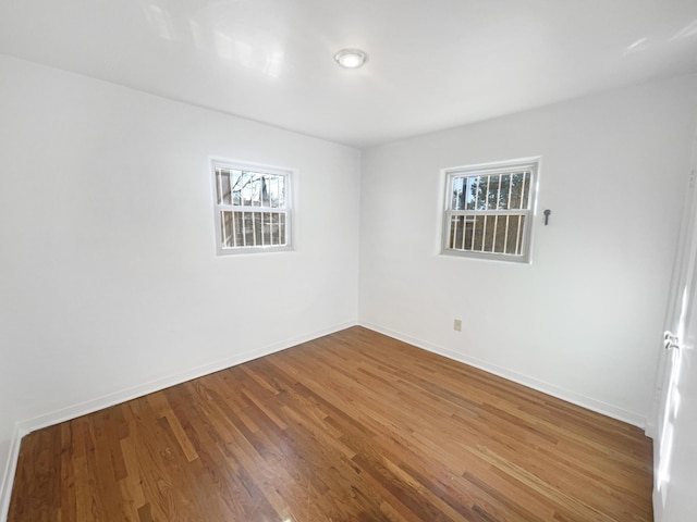 empty room with a healthy amount of sunlight, baseboards, and wood finished floors