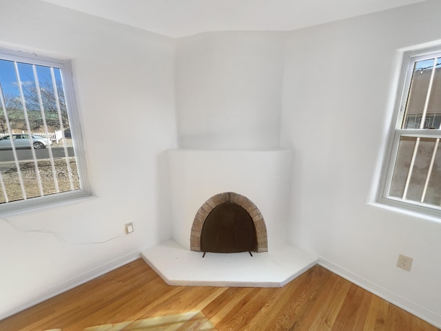 unfurnished living room with a fireplace, baseboards, and wood finished floors