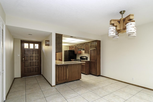 kitchen featuring black refrigerator, light tile patterned floors, kitchen peninsula, and range