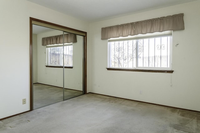 unfurnished bedroom featuring light carpet and a closet