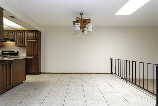 kitchen featuring dark brown cabinets, range, an inviting chandelier, and light tile patterned floors