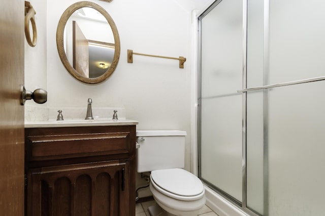 bathroom featuring tile patterned flooring, vanity, a shower with door, and toilet