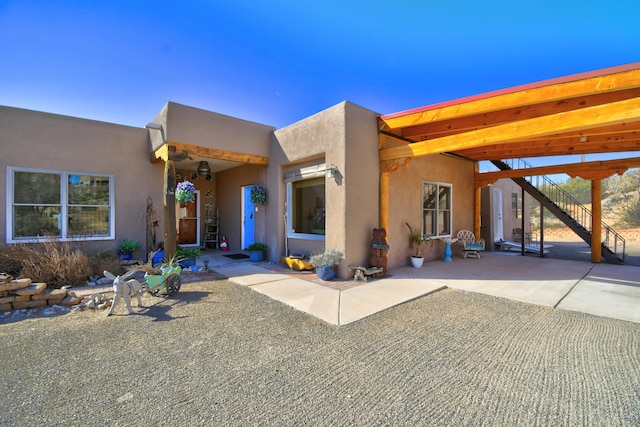 adobe home featuring stairs, a patio, and stucco siding