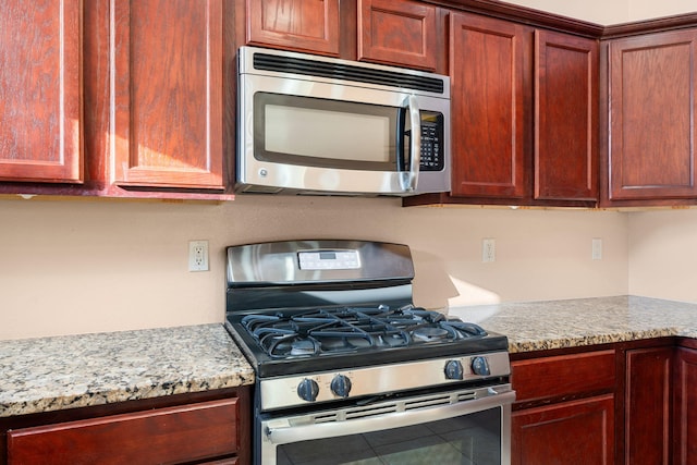 kitchen featuring stainless steel appliances, light stone countertops, and tile patterned floors